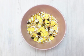 muesli with on a pink plate, top view. Muesli with fresh milk, yogurt or kefir. Muesli is made from oatmeal, a mixture of multi-grain flakes with dried fruits, nuts and sunflower seeds. on a white