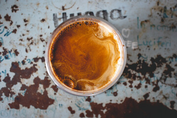 Top view of cold Dirty Latte coffee in a glass on rusty table.