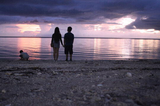 Asian couple watching the sunset at the beach.