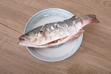 On the plate is a sea bass that is being marinated