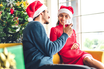 Romantic sweet couple in santa hats having fun and drinking wine glasses while celebrating new year eve and enjoying spending time together in christmas time at home