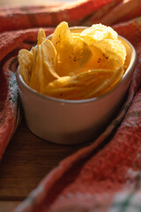 Chips de banana frita dentro de un recipiente iluminados por la luz del sol