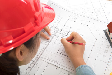 Blueprint designer wearing red hard hat at work