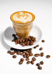latte coffee in a white mug and coffee beans on the table.