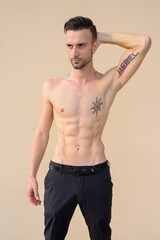 Obraz premium Portrait of handsome young man shirtless against wall