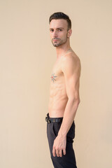 Portrait of handsome young man shirtless against wall