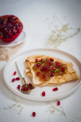 Pancakes with jam and pomegranate. Light background.