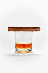 Closed up view of glass of whiskey with cigar on top on white back
