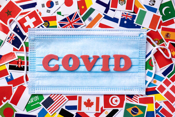 Medical masks with word covid written red colors on the background from national flags.
