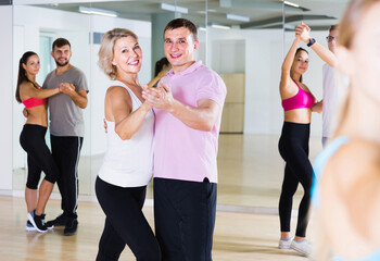 Dancing positive english couples learning salsa at dance class