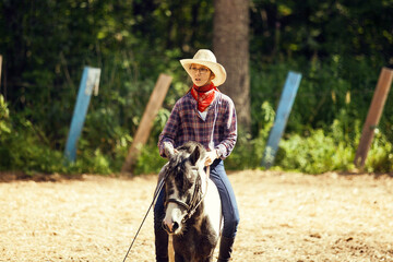 Young girl on the horse afield. Equestrian girl. Cowgirl