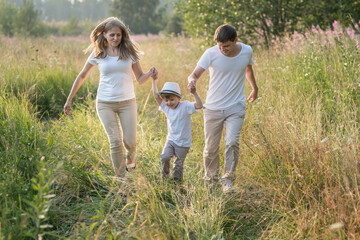 Naklejka na ściany i meble Happy family enjoying walk together at meadow in summer