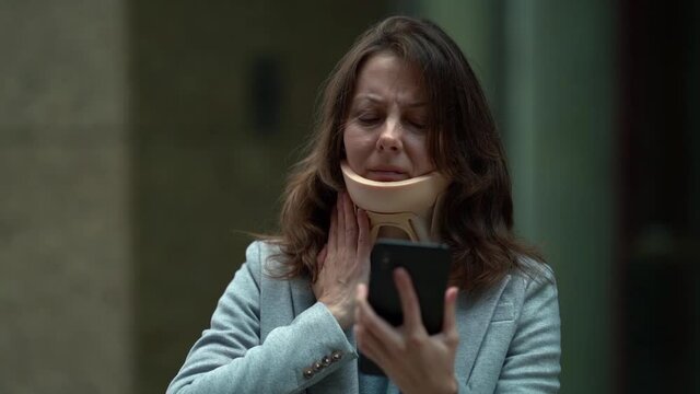 middle-aged woman with neck brace for prevention of osteochondrosis is waiting public transport on street