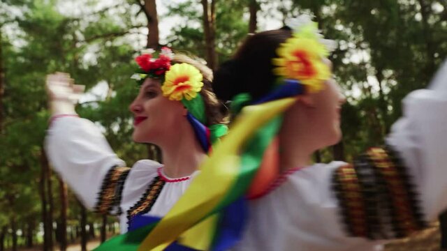 CLose up of two women in traditional costumes are dancing Ukrainian national dances