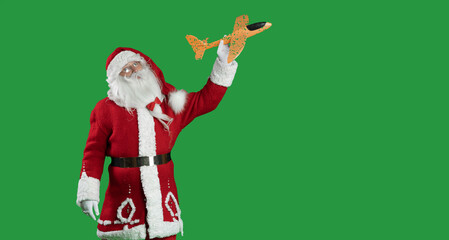 santa claus on a green background holding a toy plane playing. . Copy space. Christmas travel concept.