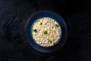 Rice with parsley garnish, overhead shot on a dark background