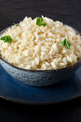 A bowl of white rice on a dark background, minimal shot