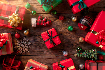 topview flatlay of present gift boxes with red color and ribbon wrap on wooden texture floor with decorative ornament new year and chiristmas festive greeting background ideas concept