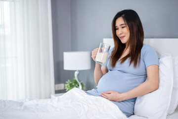 Obraz na płótnie Canvas pregnant woman drinking a milk at the window in bedroom
