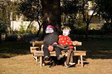 Two funny puppets sitting in a park bench