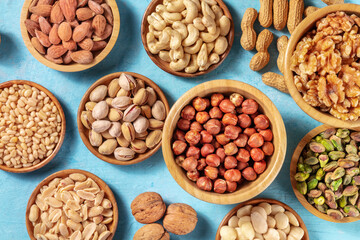 Nuts. Overhead flat lay shot of various nuts in wooden bowls, on a vibrant blue background