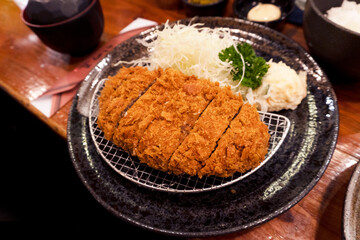 Close up to the Japanese famous meal tonkatsu mixed with pork and beef deep fried with freshness served with sides cabbage salad in the restaurant