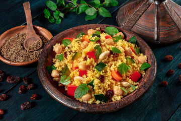 African couscous in the tagine, with spices and herbs on a dark wooden background