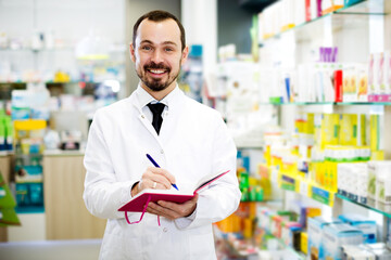 Fototapeta premium Adult male pharmacist checking assortment of drugs in pharmacy