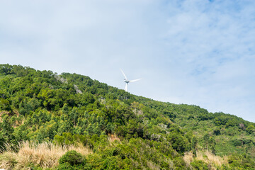 A windmill in the green mountain against blue sky in the coastline of Yangxi, Yangjiang of China