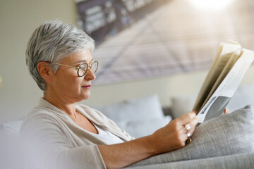 Senior woman reading newspaper, relaxed in sofa