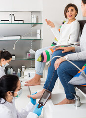smiling women getting pedicure by professional in modern beauty salon