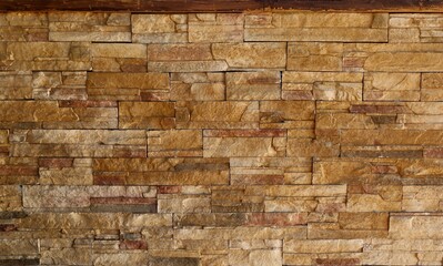 Stone wall made of striped stacked slabs of natural brown and red  rocks. Paneling for rustic home decor. Background and texture.