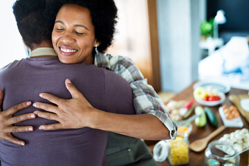 Beautiful couple are hugging and smiling while spending time in kitchen