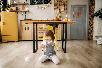 Beautiful blonde girl in waiting for Merry Christmas playing in a cozy kitchen at home
