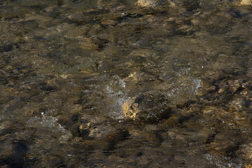 Closeup of a river in South France, flows between stones. Forms bubbles.