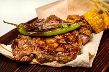 Barbecue pork ribs, corn and fries on pita bread. Close-up, selective focus