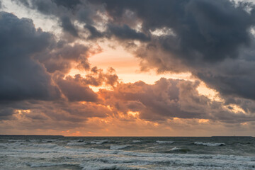 Naklejka na ściany i meble Golden sunset with dramatic cloudscape over the sea.