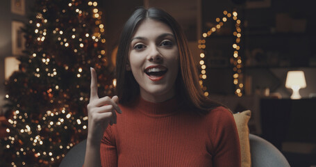 Fototapeta premium Cheerful woman pointing up and Christmas decorations