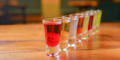 Tincture alcoholic in small shot glasses. Natural fruit alcohol drinks, shots served on a wooden table.