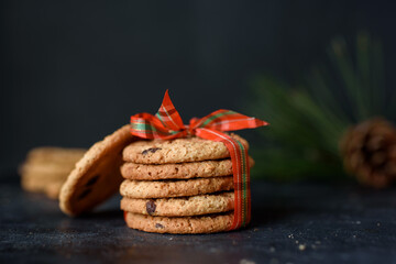 Shortbread cookies with pieces of chocolate are tied with red beautiful ribbon on a dark background. New Year's cookies.