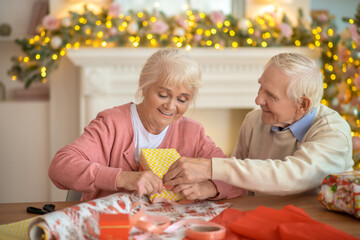 Elderly couple packing christmas gifts and enjoying