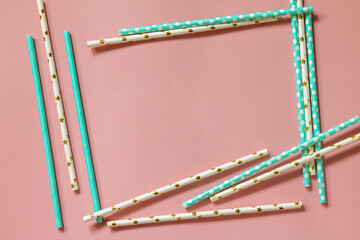 A frame of Drinking paper straws for cocktails on pink background. Top view flat lay. Copy space.