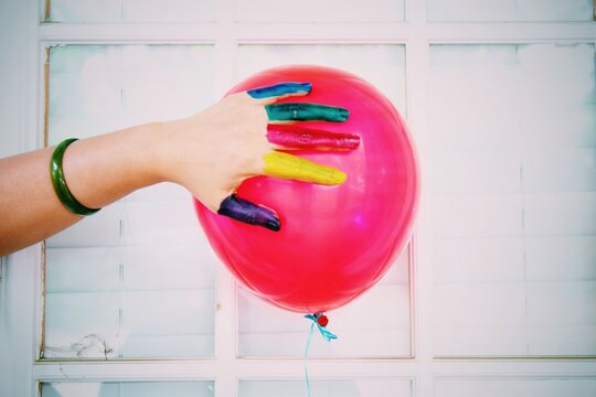 Cropped Colorful Watercolor Paints Covered Hand Touching Red Helium Balloon