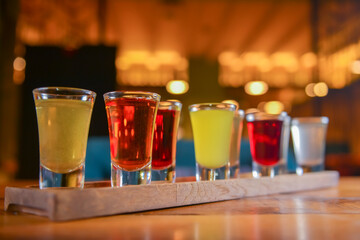 Tincture alcoholic in small shot glasses. Natural fruit alcohol drinks, shots served on a wooden table.
