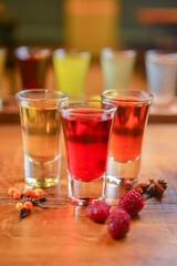 Tincture alcoholic in small shot glasses. Natural fruit alcohol drinks, shots served on a wooden table.
