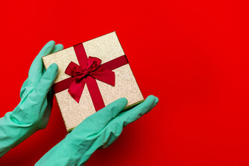 Gift box, hands in medical gloves. Preparation for the holiday during the coronavirus pandemic.