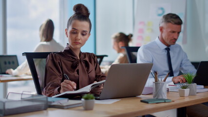 Businesswoman making notes in business diary. Business woman working on laptop