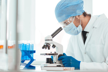 close up. scientist looking into the eyepiece of a microscope.