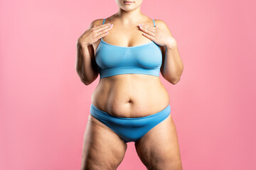 Fat woman in blue underwear on pink background, overweight female body