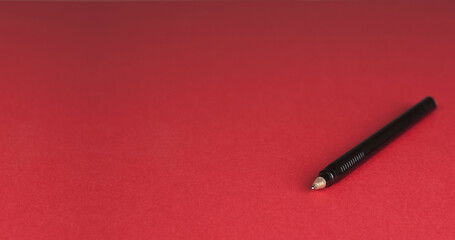 Black pen on a red background. Close-up.